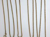 plusieurs types de colliers en or disposés sur une surface blanche