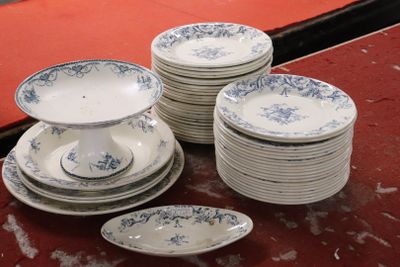 Plusieurs assiettes et bols sont empilés sur une table recouverte d'une nappe rouge.
