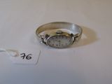 une montre-bracelet en argent posée sur une table blanche, avec une étiquette de prix