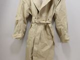 beige trench coat hanging on a hanger on a wall