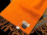 an orange scarf with a tag on it sitting on a black surface