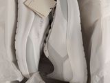 des baskets blanches dans une boîte, avec une étiquette posée dessus