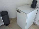 un petit réfrigérateur blanc dans le coin d'une pièce