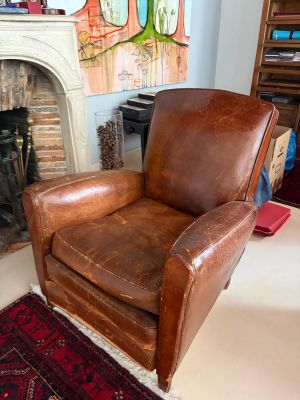 un fauteuil en cuir marron placé devant une cheminée