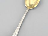 a silver spoon with a gold handle on a gray surface