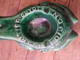 a green bird shaped ashtray on a wooden floor