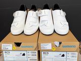 trois paires de chaussures blanches posées sur une boîte en carton
