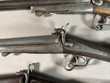 several old guns are lined up on a white surface