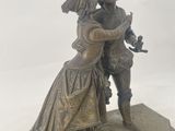 bronze statue of a man and a woman embracing on a pedestal