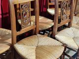 Quatre chaises en bois avec des assises en osier sont disposées devant un rideau rouge
