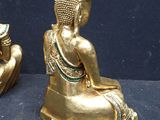 two gold statues of buddhas sitting on a blue surface