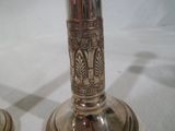 deux bougeoirs en argent posés sur une table blanche