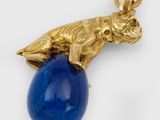 a close up of a gold and lapis pendant with a blue stone