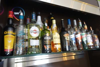 Des bouteilles d'alcool sont alignées sur une étagère dans un bar