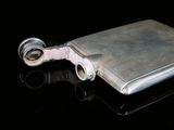 a silver flask with a metal handle on a black surface