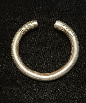 gros plan d'un bracelet en argent sur une surface noire