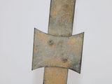 a metal cross on a pole on a white surface