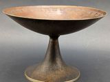 an old black and gold bowl sitting on top of a table