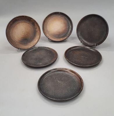 four different sized metal plates sitting next to each other on a white surface