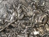 a metal plaque with a picture of a group of men on horses