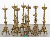 several brass candles are lined up in a row on the floor