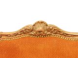 an orange couch with gold trim and a gold headboard