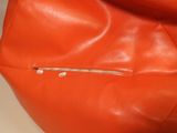 an orange leather bag with a zipper on the inside of it