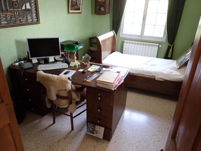 une photo d'une chambre à coucher avec un lit, un bureau et un ordinateur