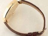 a close up of a watch on a white surface with a brown strap