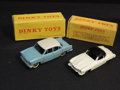 two toy cars are sitting next to a box of dinky toys