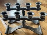 a metal candelab with six candles on it on a wooden floor