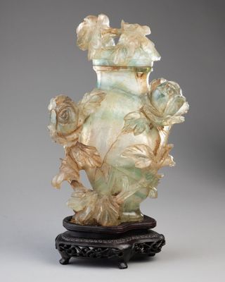 un vase vert orné de fleurs, posé sur un socle