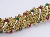 a close up of a gold bracelet with green and red stones