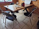 une table avec des chaises et un ordinateur portable posé dessus, dans une pièce