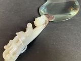 an image of a white jade figurine with a magnifying glass in the background