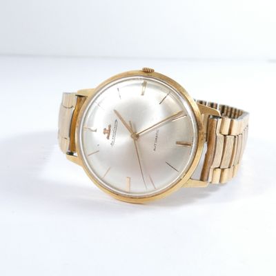 a close up of a gold watch on a white surface