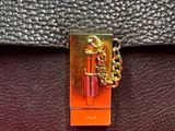 a close up of a black and orange purse on a pink surface