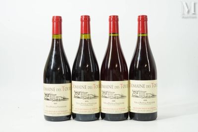 quatre bouteilles de vin sont alignées sur une surface blanche