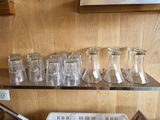 bottles and glasses are lined up on a shelf in a kitchen