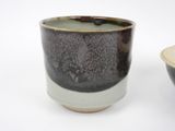 a black and white cup sitting next to a brown and white bowl