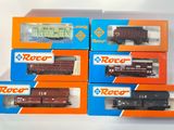 quatre boîtes contenant des trains miniatures, posées sur une surface blanche