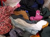a pile of clothes that is sitting on a bed