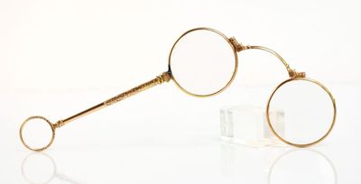 une paire de lunettes plaquées or posées sur une surface transparente avec des reflets