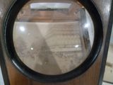 une horloge en bois surmontée d'une loupe