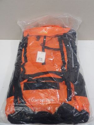 un sac à dos orange et noir, emballé dans du plastique, posé sur une table