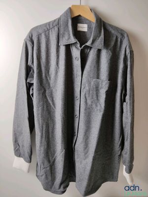 La chemise est suspendue à un cintre accroché au mur.