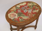 a small wooden table with a red and yellow floral cushion