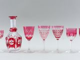 several wine glasses and a decanter are lined up in a row