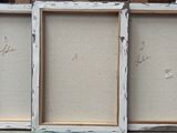 three framed paintings of different sizes and colors are on a table