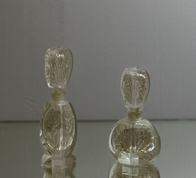 two glass bottles sitting on a glass table